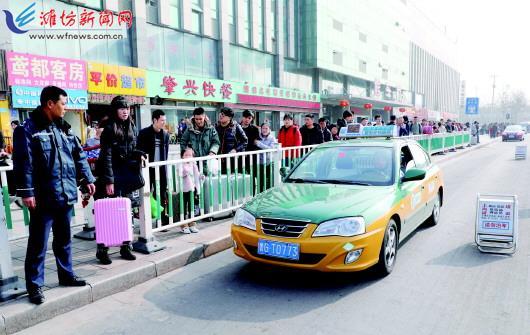 在潍坊联运汽车站客运站路边,乘客们排队乘坐出租车.